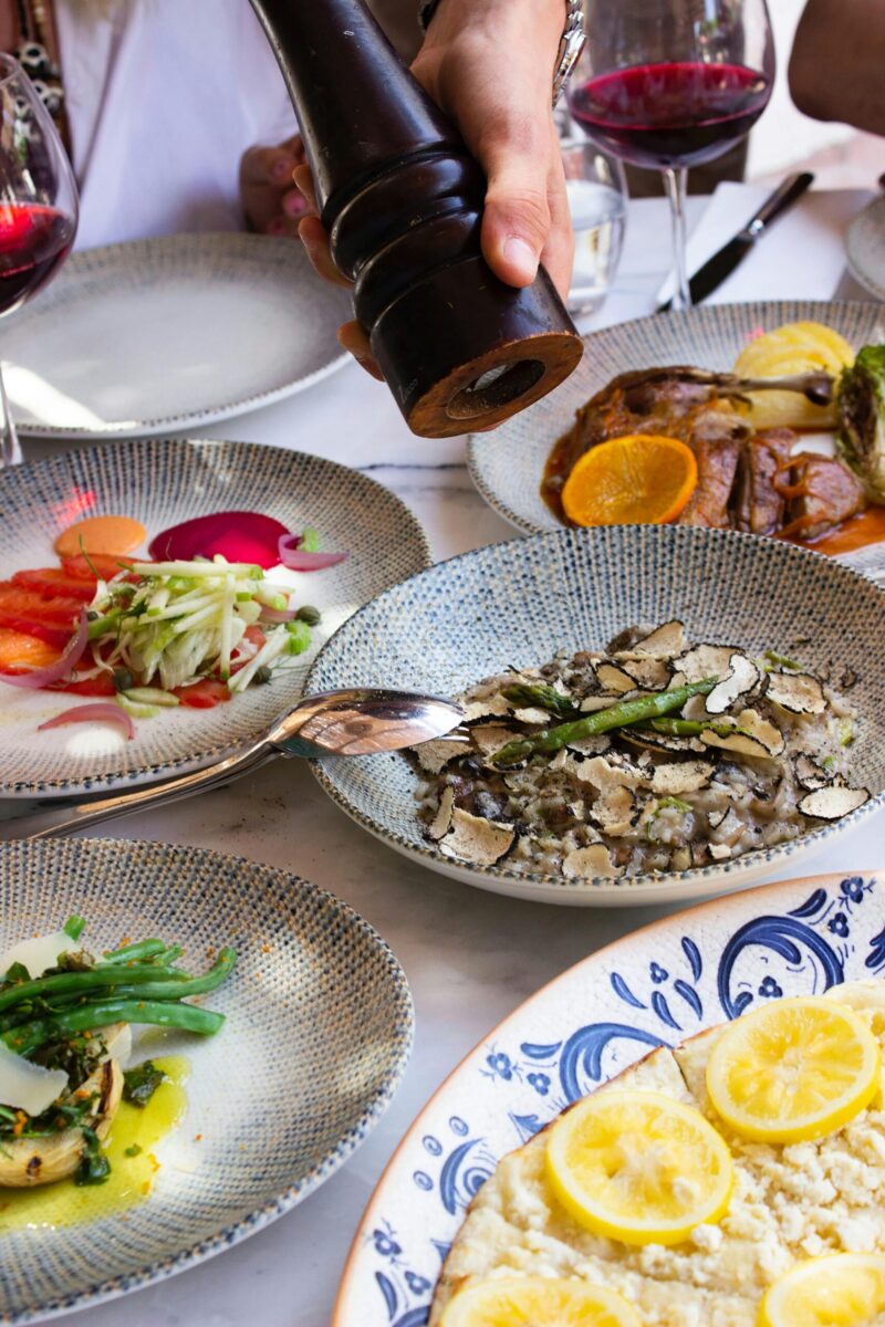 Photo by Doğu Tuncer A luxurious dining experience featuring gourmet dishes and red wine on elegantly set tables.
