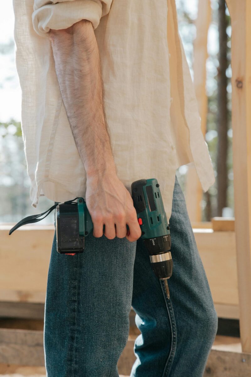 Photo by Ron Lach A carpenter holding a power drill at a construction site during daylight.